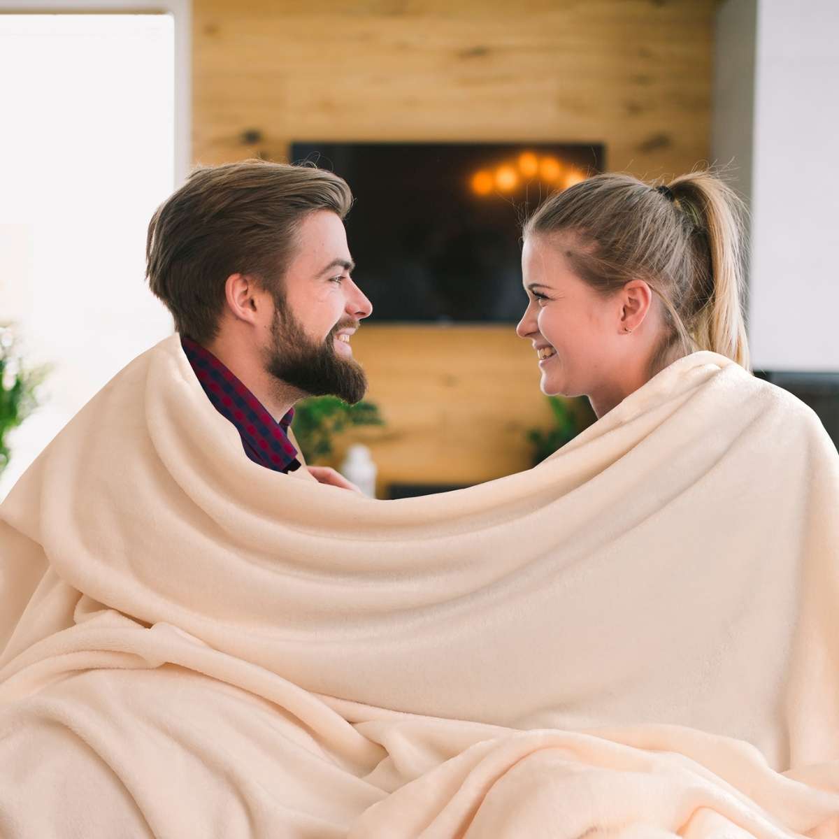 hombre y mujer sonriendose envueltos en una cobija hueso king size