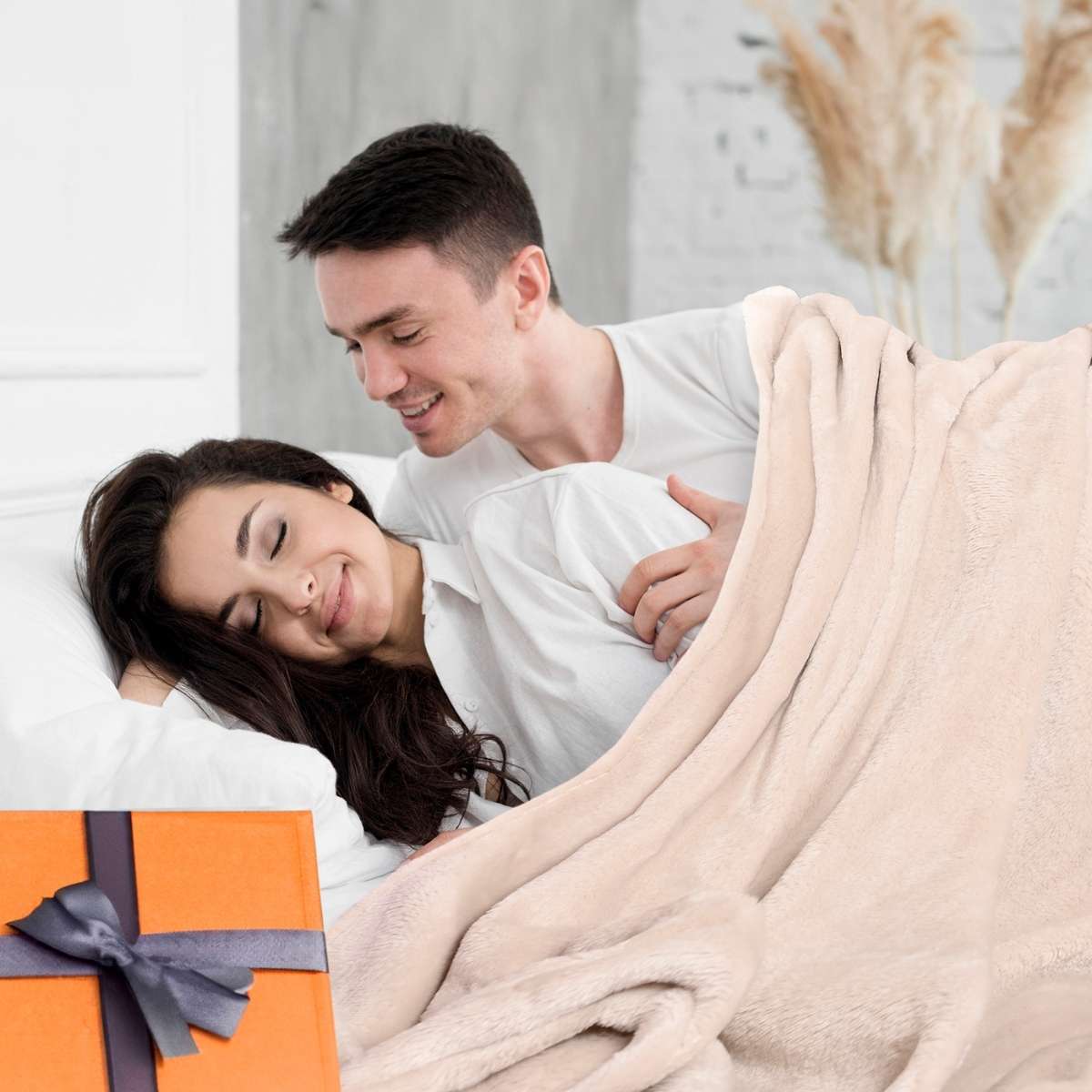 Hombre abrazando a su esposa mientras comparten un momento cálido bajo la cobija de flanel color arena tamaño queen size