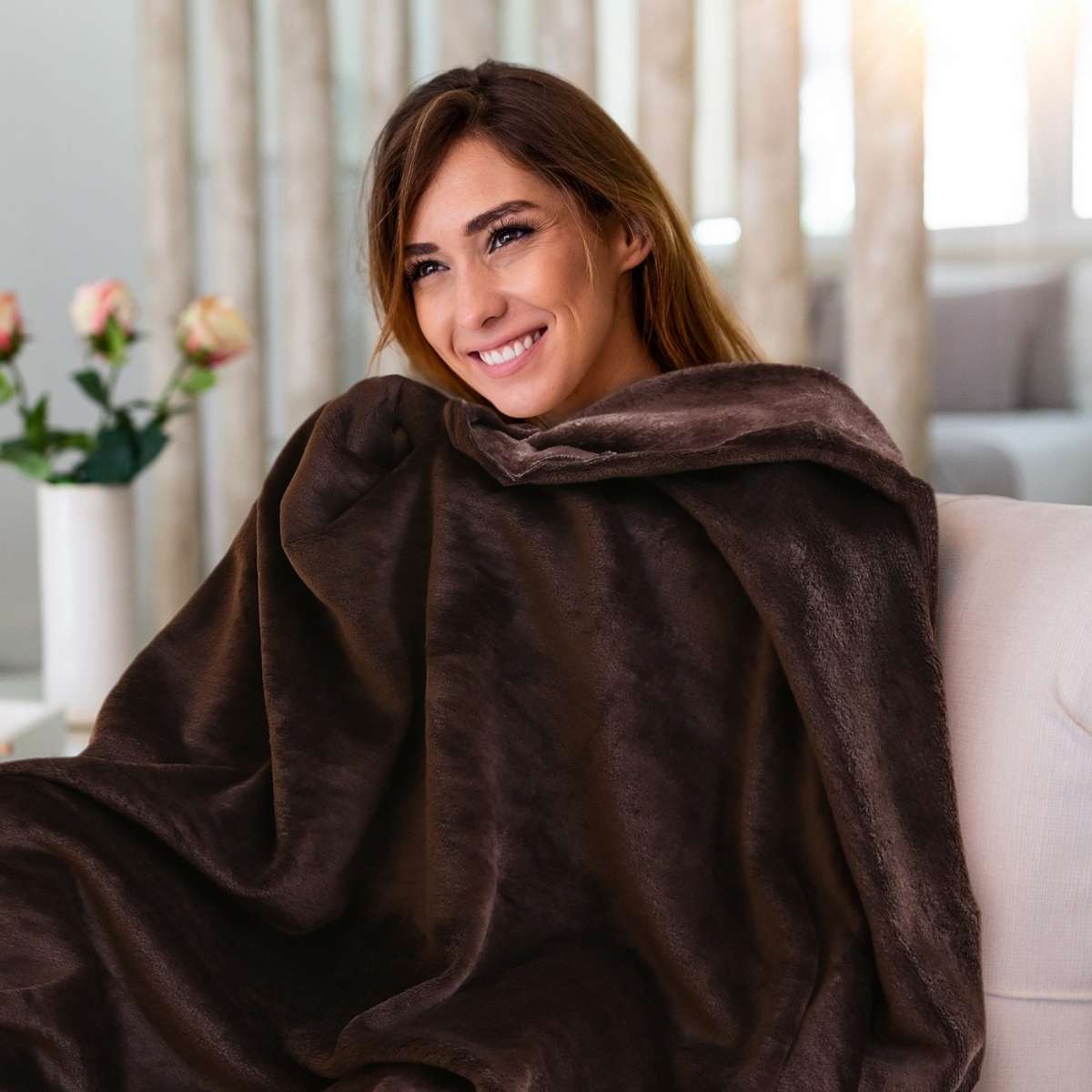 Mujer disfrutando de una cobija de flanel color café tamaño king size en un sillón