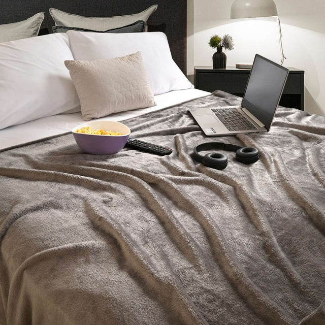 Cobija de flanel color gris claro tamaño matrimonial  tendida sobre una cama