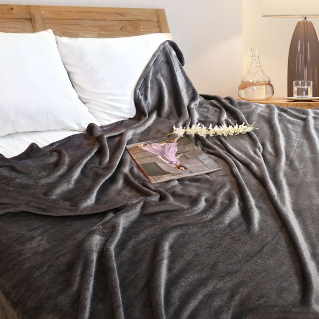 Cobija de flanel color gris oscuro tamaño matrimonial  tendida sobre una cama