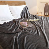Cobija de flanel color gris oscuro tamaño matrimonial  tendida sobre una cama