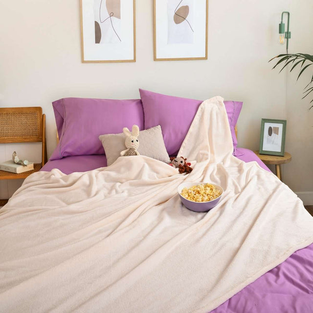 Cobija de flanel color hueso tamaño matrimonial  tendida sobre una cama