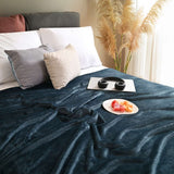 Cobija de flanel color petróleo tamaño individual tendida sobre una cama