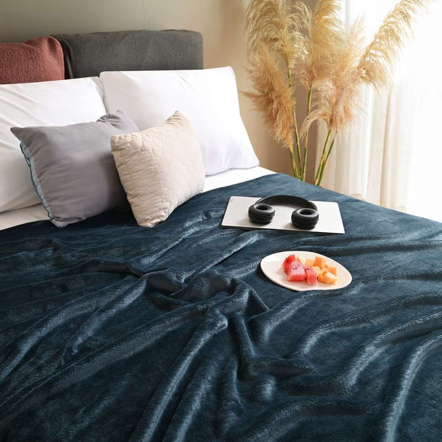 Cobija de flanel color petróleo tamaño matrimonial  tendida sobre una cama