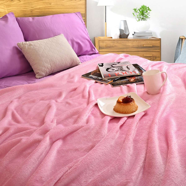Cobija de flanel color rosa tamaño matrimonial  tendida sobre una cama