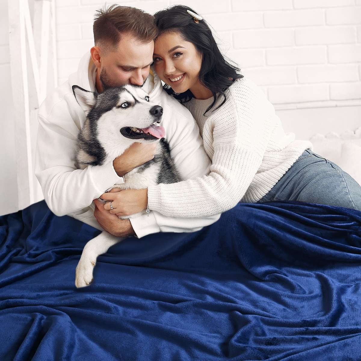 Familia reunida en un acogedor sillón, con la madre agarrando a su perro, todos cubriéndose con una cobija  matrimonial  de color marino para mayor calidez y confort