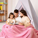 Padres sentados con su hija, compartiendo un momento de lectura bajo una acogedora cobija rosa matrimonial , disfrutando juntos de un cuento