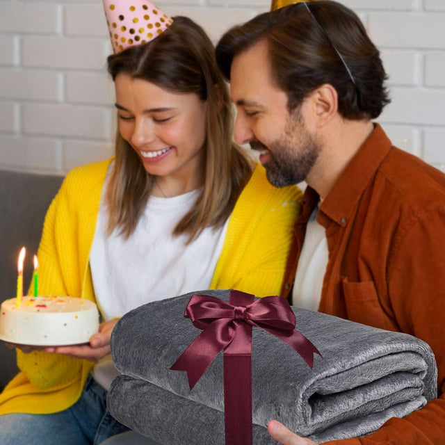 Papá regalando a su hijo en su cumpleaños una cobija de color gris oscuro matrimonial  como gesto de cariño y calidez