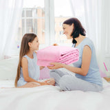 Madre regalando una cobija matrimonial  alegremente a su hija, ambas sonriendo con alegría y complicidad ante el gesto cálido y amoroso